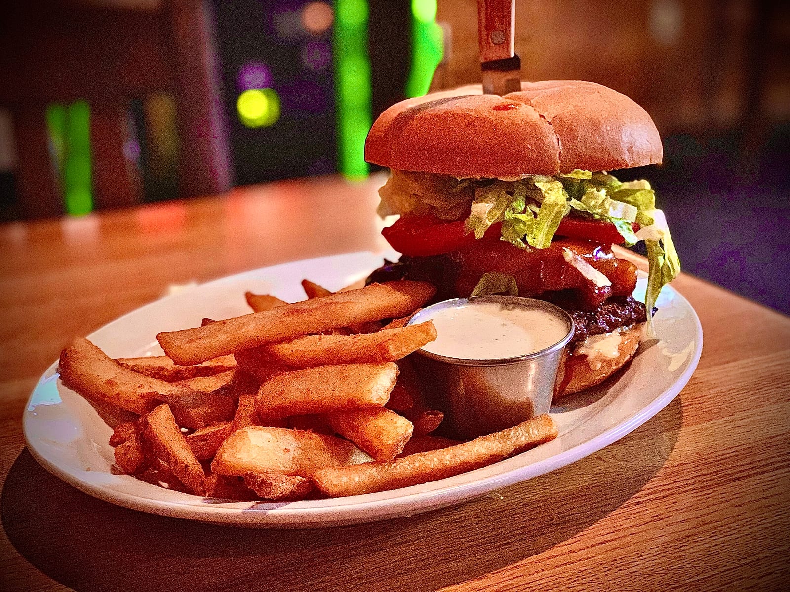 Tall burger with lettuce and tomato served with fries and dipping sauce